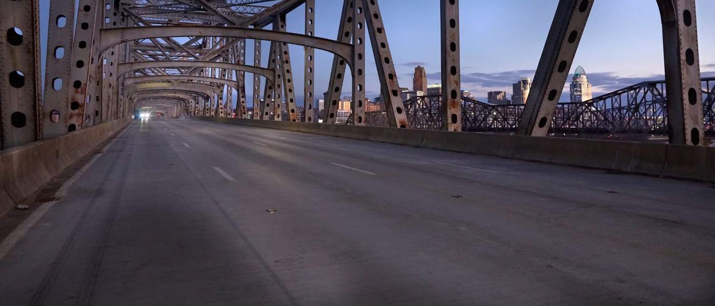 View down a steel truss bridge toward a city skyline